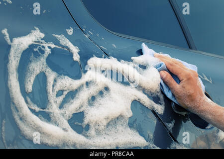 Auto waschen mit einem blauen Schwamm. Weibliche Hand wäscht die Maschine mit Seife Schaum. Toning Stockfoto