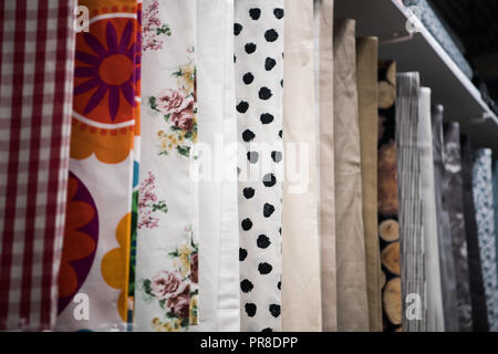 Bunten Vorhang Proben hängen von Aufhängungen auf der Schiene in einem display Store mehrere Farbe fabric Texture Samples Auswahl Stoffe für Inneneinrichtung, Vorhänge, Tüll- und Polstermöbelindustrie. Stockfoto