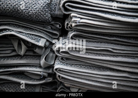 Natürliche reine Bettwäsche Handtücher, Servietten Tischdecke. Kleine Unternehmen. Stapel der gestreiften weiß grau Bettwäsche aus Baumwolle auf Stoff Hintergrund. Essen foto Requisiten Stockfoto