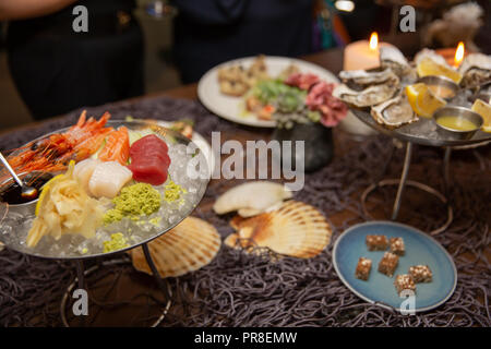 Sashimi gemischt in Scheiben Fisch und Garnelen auf Eis im schwarzen Schüssel. Sashimi Lachs Thunfisch Hamachi Garnelen und Surf Ruhig, roher Fisch, japanisch Essen in asiatischen Rest Stockfoto