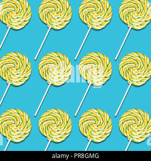 Symmetrische Anordnung der gelben und grünen lollipop Bonbons auf Türkisfarbenem Hintergrund, bunten süßen Speisen Textur Stockfoto