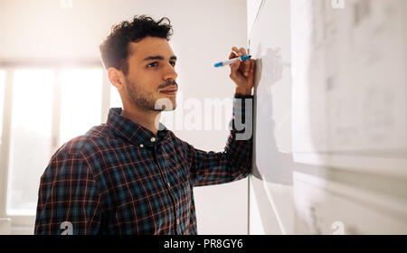 Unternehmer stehen in der Nähe ein Whiteboard mit einem Markierstift im Amt. Unternehmer Diskussion von Ideen und Pläne auf einem Brett. Stockfoto