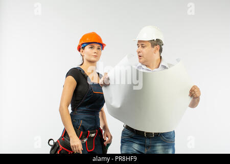 Fremdfirmen Menschen über den Plan der Gebäude mit weißem Hintergrund. Meister mit builder Frau Helme tragen. Stockfoto