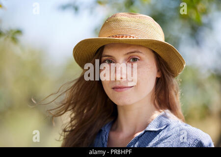 Attraktive junge Frau Bauer im Stroh Hut und blaues T-Shirt im Freien Stockfoto