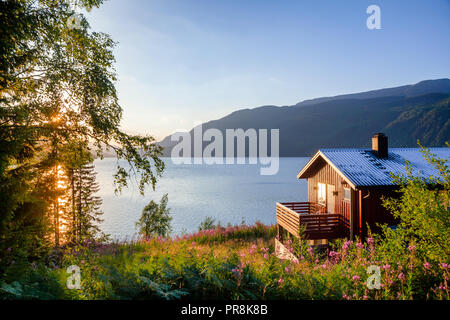 Norwegische Holz- Summer House (Hytte) mit Terrasse mit Blick auf den malerischen See bei Sonnenuntergang, Telemark, Norwegen, Skandinavien Stockfoto