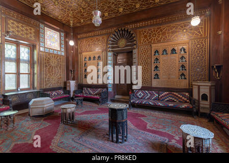 Manial Palast von Prinz Mohammed Ali. Gäste Halle mit Holz verzierte Decken, Holz- reich verzierten Tür, Laternen, bunt verzierten Sofas, Kaffee Tabellen Stockfoto