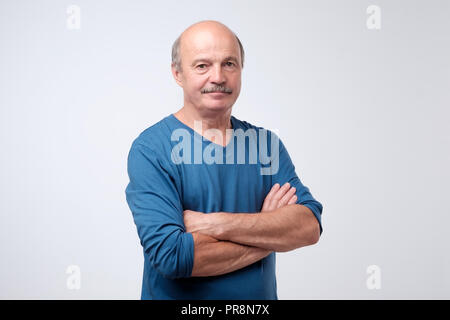 Portrait von reifen europäischen Mann mit Schnurrbart im blauen Hemd seine Arme überquert haben, an der Kamera auf der Suche Stockfoto