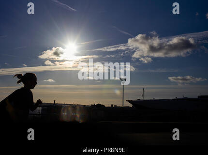 Jogger laufen Vergangenheit mit Sun direkt hinter Liverpool Pier Head Stockfoto
