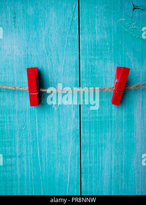 Zwei Wäscheklammern auf Seil mit Holz wand hintergrund, Vintage clip, rot Wäscheklammer. Stockfoto