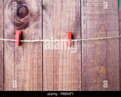 Zwei Wäscheklammern auf Seil mit Holz wand hintergrund, Vintage clip, rot Wäscheklammer. Stockfoto