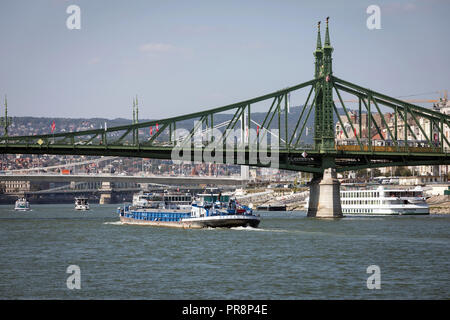 Ein Lastkahn verläuft unter der Brücke oder Szabadság híd auf der Donau in Budapest Stockfoto