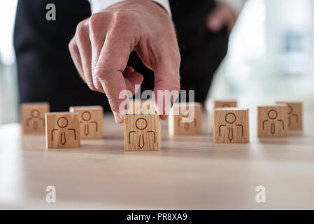 Human Resources Konzept - Geschäftsmann arrangieren Holzwürfel mit Menschen Symbol auf Büro Schreibtisch. Stockfoto