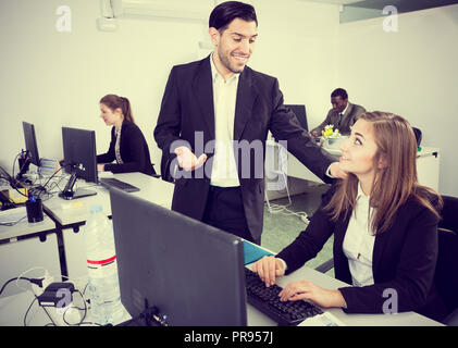 Gut aussehender bärtiger Mann reden und flirten mit attraktiven lächelnde Frau, die in einer Co-Arbeitsbereich Stockfoto