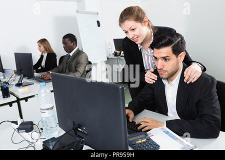 Positive lächelnde Geschäftsfrau Flirten mit Spanischer männlichen Kollegen während der Arbeit in der modernen Coworking Space Stockfoto