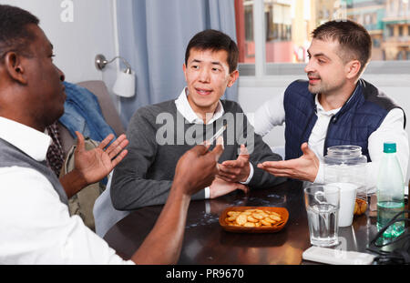 Gerne männliche Freunde genießen сonversation am Tisch im Interieur Stockfoto