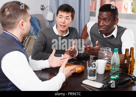 Gerne männliche Freunde genießen сonversation am Tisch im Interieur Stockfoto