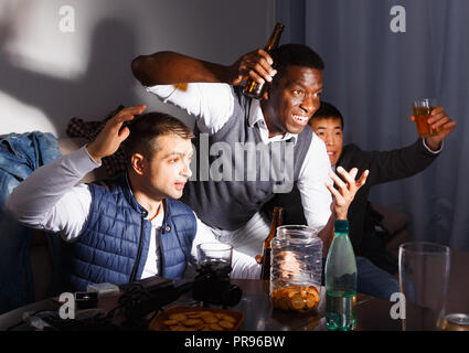 Erhaben männliche Freunde tv gemeinsam zu Hause, Bier genießen mit Snacks drinnen spät in der Nacht Stockfoto