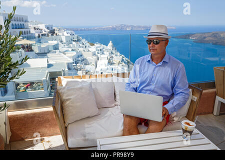 Mann in einem Café am Meer an einem Notebook arbeitet und trinken Kaffee Stockfoto