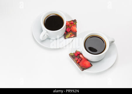 Zwei Tassen Kaffee und handgemachte Schokolade mit getrockneten Erdbeeren und Beeren auf weißem Hintergrund Stockfoto