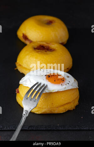 Bulz, eine traditionelle rumänische Speisen aus polenta Kugeln gefüllt mit Schafskäse und gebratene geräucherte Wurst, und serviert mit einem weichen Spiegelei. Stockfoto