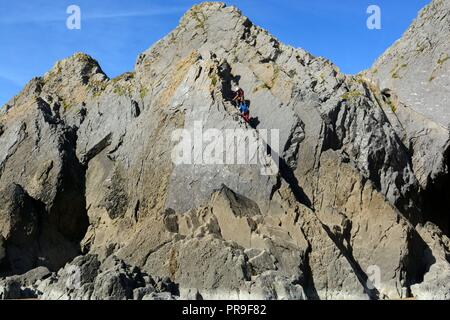 Zwei Männer klettern Bergsteiger auf drei Felsen Three Cliffs Bay Halbinsel Gower Wales Cymru GROSSBRITANNIEN GB Stockfoto