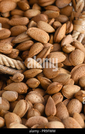 Makro von gesunden organischen Mandeln in der Schale full frame Bild mit einem alten Weidenkörbe vertikal mit selektiven Fokus im Hintergrund und foregroun Stockfoto