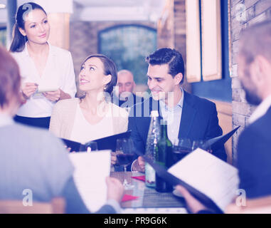 Mitarbeiter Kellnerin Frau, um von positiven Gäste im Restaurant Stockfoto