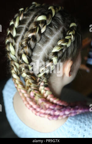 Eine Frisur aus dickem Zopf mit einem Kanekalon für ein Mädchen, fünf Zöpfe mit einer Verflechtung von künstlichen Materialien. Boxing Zöpfe, Trends in der hairstyl Stockfoto