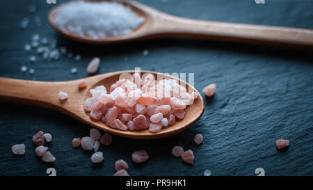 In der Nähe des Himalaya Pink salt in Löffel aus Holz, auf dunklem Hintergrund Stockfoto