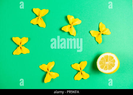 Kreative Sommer Layout aus Zitrone und farbigen Nudeln Grieß Papillon auf hell grün hinterlegt. Obst minimalen Begriff Stockfoto