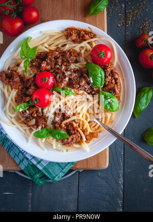 Italienische Spaghetti mit Tomatensauce, Parmesan und frischem Basilikum auf der Oberseite, auf dunklem Hintergrund, Ansicht von oben Stockfoto