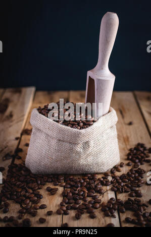 Kaffeebohnen in Jute sack auf Holz- Hintergrund Stockfoto