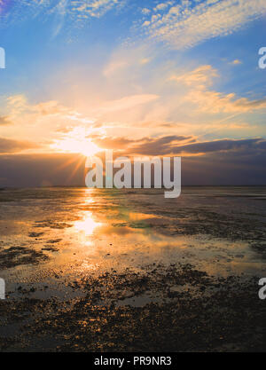 Die Sonne über dem Meer während des Magic Hour mit erstaunlichen Reflexionen Stockfoto