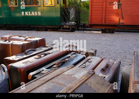 Gepäck mit Koffern vor einem alten Zug mit einem Wagen und einem grünen zweiter Klasse Passagier wagen. Stockfoto