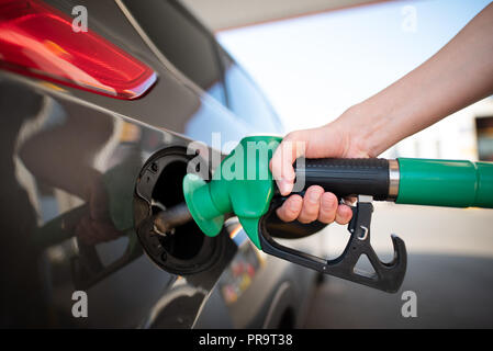 Nahaufnahme der Mann pumpen Benzin im Auto an der Tankstelle. Gas Pumpe Düse in den Kraftstofftank ein graues Auto Stockfoto