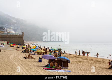 SESIMBRA, PORTUGAL - ca. September 2018: Nicht identifizierte Personen am Strand an einem nebligen Tag Stockfoto