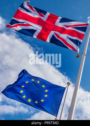 BREXIT KONZEPT FAHNEN GROSSBRITANNIEN Union Jack Flagge fliegen hoch über EU-europäischen Flagge in eine steife Brise an einem sonnigen Tag mit blauen Himmel von Wolken unterteilt Stockfoto