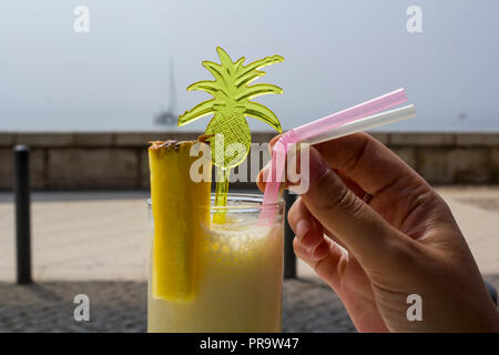 Frau hand Trinken einer Ananas smoothie Cocktail am Strand Stockfoto