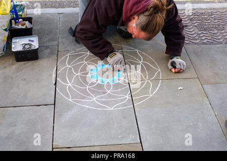 Artist Beginn seiner Mandala auf dem Bürgersteig zu machen. Glastonbury, Somerset, Großbritannien Stockfoto