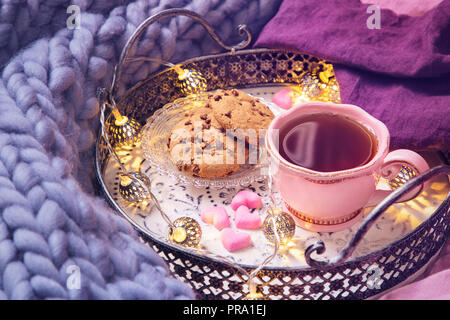 Rosa Tasse Tee, Plätzchen, Garland und Wolldecke Stockfoto