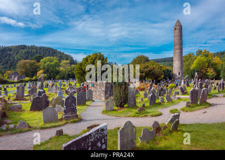 Stein runden Turm und einige Ruinen einer monastischen Siedlung, die ursprünglich im 6. Jahrhundert in Glendalough Tal gebaut, County Wicklow, Irland Stockfoto