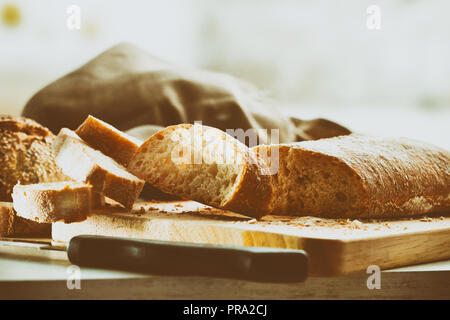 Geschnittenes Brot auf Schneidebrett auf der Bank aus einer Küche traditionelle Jahrgang. Vorderansicht. Horizontale Zusammensetzung Stockfoto