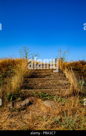 Treppen auf der Wiese. Ungleichmäßige Schritte vom Boden führen auf den Hügel. Stockfoto