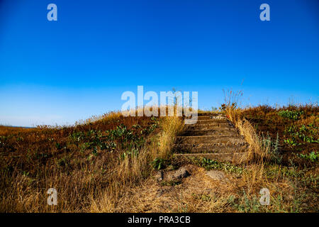 Treppen auf der Wiese. Ungleichmäßige Schritte vom Boden führen auf den Hügel. Stockfoto