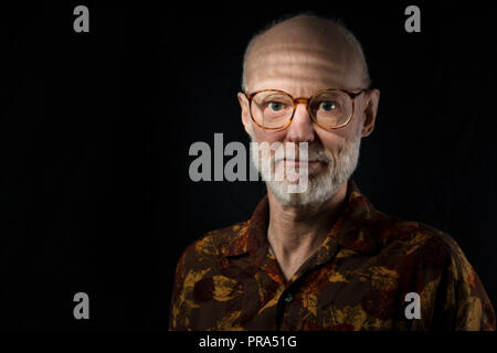 Portrait von älteren Mann in casual braun Shirt auf schwarzem Hintergrund Stockfoto
