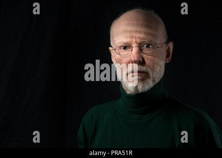 Porträt von Ernst Befragung älterer Mann auf schwarzem Hintergrund Stockfoto