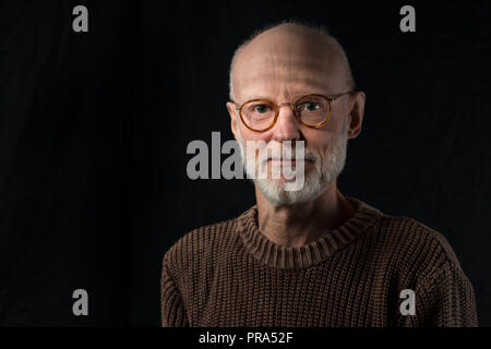 Portrait von älteren Mann an der Kamera schaut auf schwarzem Hintergrund Stockfoto