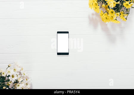 Blick von oben auf die smart phone mit leerer Bildschirm unter Blumensträuße von Aster Blumen auf weißem Holz- Hintergrund. Flach blumen Mock-up mit Platz für Text auf t Stockfoto