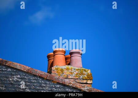 Satz von vier Terrakotta Schornsteine auf einem Dach, klaren, blauen Himmel Hintergrund für Kopie Raum ideal für Werbung konzentrieren sich auf Themen Stockfoto