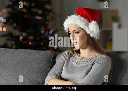 Trauriges Mädchen in der Weihnachtszeit in der Nacht auf einer Couch im Wohnzimmer zu Hause sitzen Stockfoto